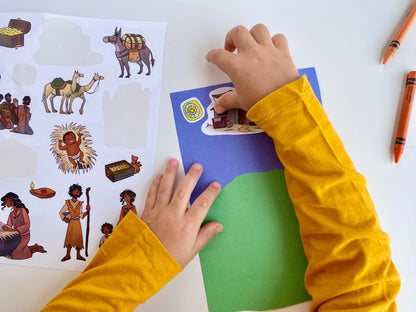 Child placing stickers on blue paper with crayons nearby
